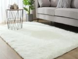 tapis blanc à poils longs dans un salon avec un canapé et une table