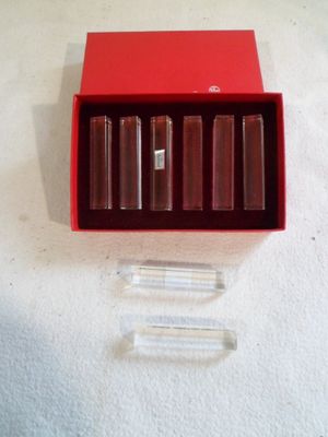 une boîte rouge contenant quatre rouges à lèvres, posée sur une surface blanche