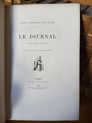 un livre ouvert posé sur une table en bois, à côté d'une pile de livres