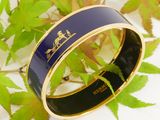 a close up of a black and gold bracelet with a horse on it