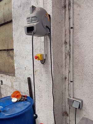 un fût bleu posé contre un mur sur lequel est fixé un compteur d'eau