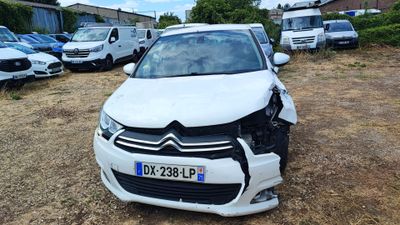 a white car that has been damaged and is sitting in the dirt