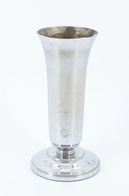 un vase en argent posé sur une surface blanche