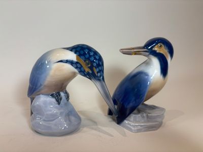 two figurines of birds that are sitting on a rock