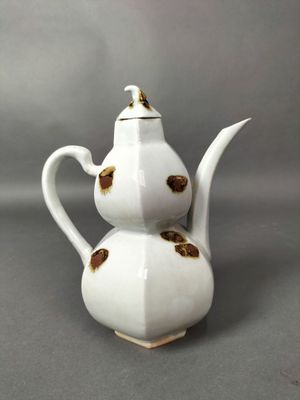 une théière blanche ornée d'un motif doré
