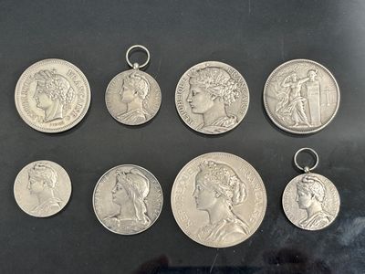 six silver coins of different sizes and shapes on a black surface