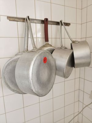 des casseroles et des poêles suspendues à une étagère dans une cuisine