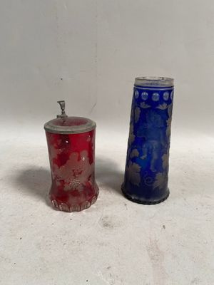une paire de vases en verre bleu et rouge posés sur une surface blanche