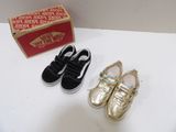 deux paires de chaussures dorées et noires posées à côté d'une boîte