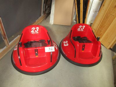 Deux autos tamponneuses rouges sont garées sur le sol d'un garage.