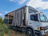 a truck that is parked in a field with a tarp on the back of it