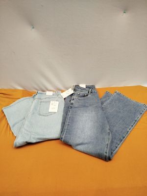 trois paires de jeans posées sur un lit recouvert de draps orange