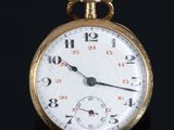 gros plan d'une montre de poche en or sur une surface noire