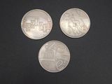 three silver coins sitting on top of a black surface