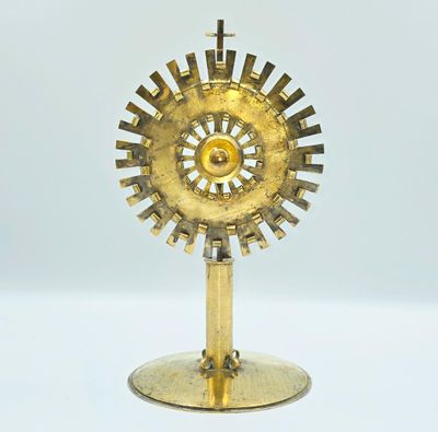une image représentant une horloge dorée posée sur un socle, sur une surface blanche