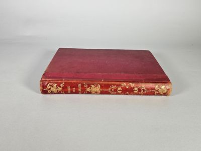 un vieux livre rouge posé sur une table blanche