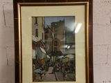 tableau représentant une scène de rue, encadré et accroché au mur