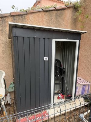 une petite remise avec un barbecue à l'intérieur, près d'une clôture