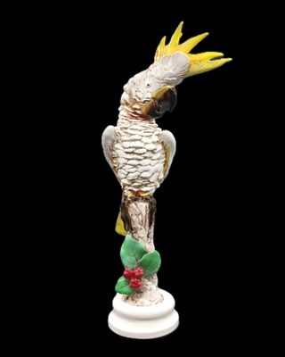 une figurine représentant un cacatoès jaune et blanc perché sur une branche