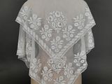 a close up of a white lace shawl on a mannequin