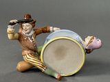 a figurine of a man sitting on the ground with a drum