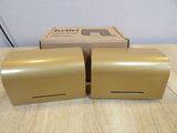two gold paper dispensers sitting on top of a wooden table