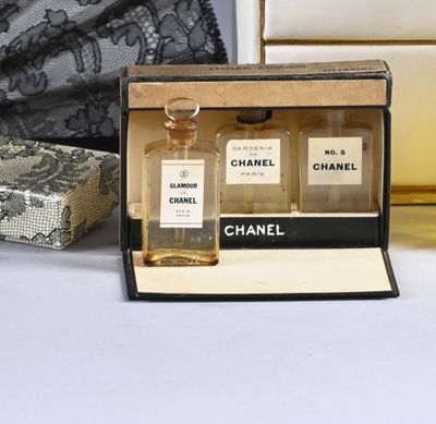 two bottles of chanel perfume sitting on a table next to a purse