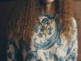 a woman with long curly hair wearing a blue and white sweater