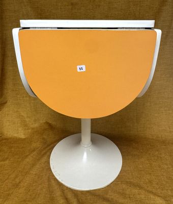 une table orange et blanche, avec un piètement blanc, sur un fond marron