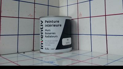 un pot de peinture posé sur un mur carrelé