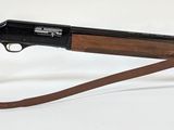 le fusil repose sur un support en verre posé sur une surface blanche