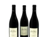 three bottles of wine are lined up on a white surface