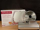 a silver food slicer sitting on a table next to a box