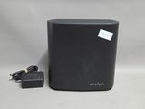 un gros plan d'une enceinte noire avec un chargeur posée sur une surface blanche