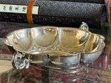 a silver bowl sitting on a glass table with books in the background