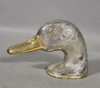 a silver and gold duck head on a white surface