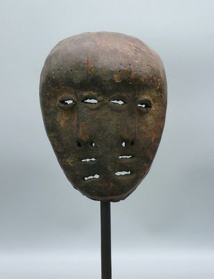 une image représentant un masque posé sur un support, sur fond gris