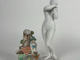 a statue of a woman standing next to a figurine of a man