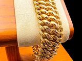 a gold bracelet on a wooden stand with a coin on it