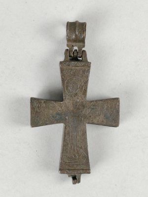 une vieille croix en métal sur laquelle est perché un oiseau