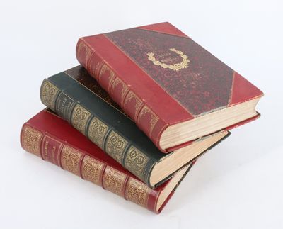 trois vieux livres empilés sur une surface blanche