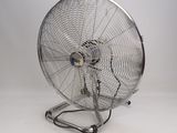 un ventilateur métallique posé sur une surface blanche