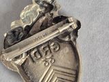 a silver pin with a sword and shield on it