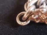 a close up of a silver and gold necklace on a black cloth