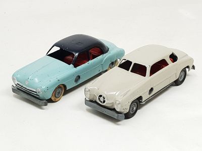 two toy cars sitting next to each other on a white surface