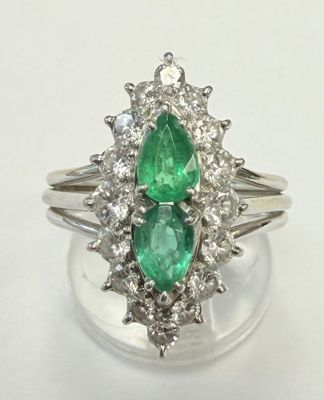 un gros plan d'une bague sertie de deux émeraudes et de diamants