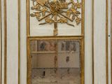 un miroir au milieu d'une armoire blanche aux bordures dorées