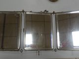 three mirrors hanging on a wall with a clock in the background