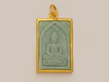 a close up of a gold and green buddha pendant on a white background