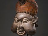 an image of a wooden mask on a stand with a gray background
